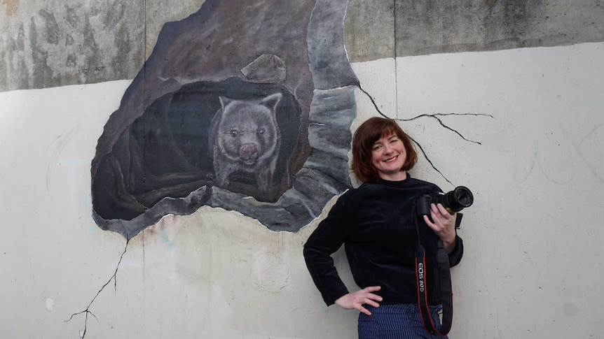 Artist Jimmi Buscombe next to the accidental wombat mural in a Warrnambool underpass