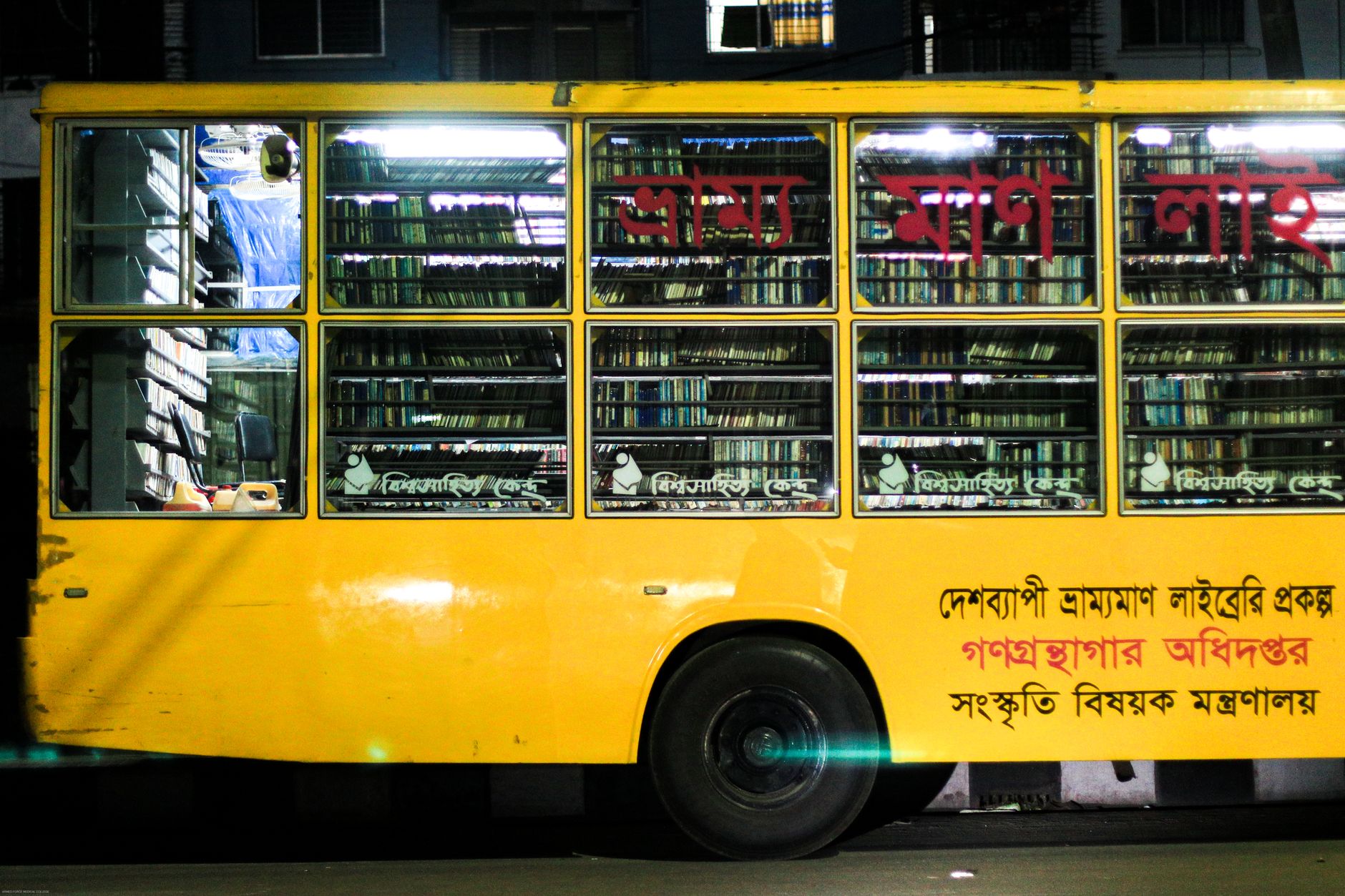 A yellow bus converted into a cozy mobile library with wooden bookshelves filled with books