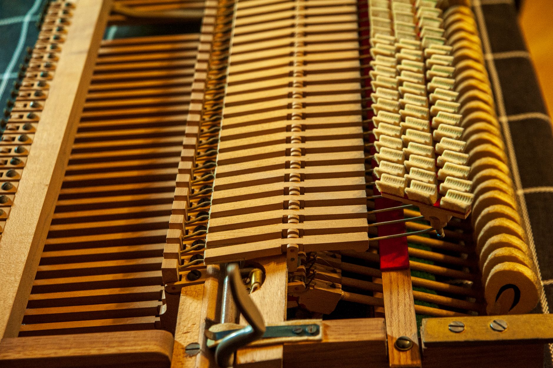 Hands carefully adjusting the wooden pins and felts inside an upright acoustic piano